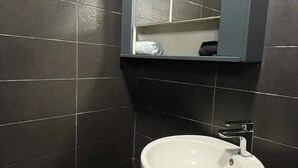 Un bany modern amb parets de rajola fosca, un envàs de pedra blanca i un mirall sobre l'envàs.