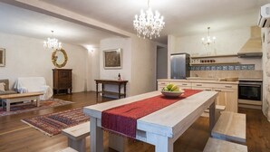 Un vaste salon doté d’un plancher en bois, d’une table à manger agrémentée d’un chemin de table rouge et d’un coin cuisine équipé d’appareils électroménagers modernes.