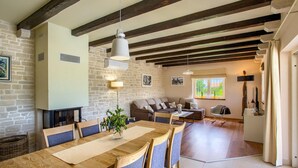 Un'area pranzo con un tavolo di legno lungo, sedie e un lampadario.