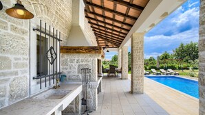 Un'area esterna coperta con pareti in pietra, una piscina e un’area salotto all'aperto.