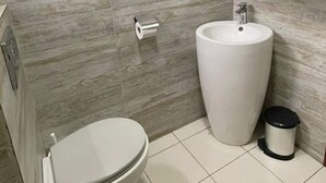 Ein Badezimmer mit Toilette, Waschbecken und Mülleimer.