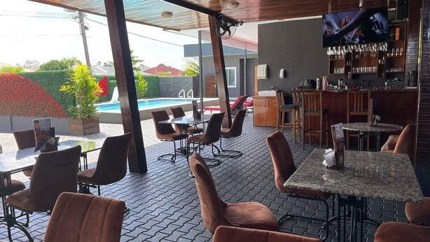 Ein Außenbereich mit Tischen, Stühlen, einem Pool und einer Bar inklusive Fernseher.