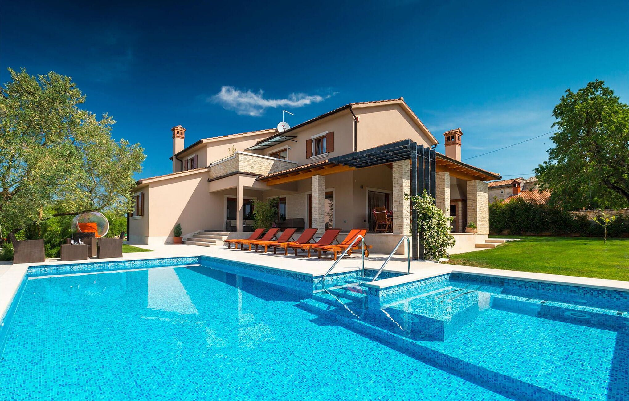 A modern two-story house with a swimming pool, outdoor seating, and a well-maintained garden.