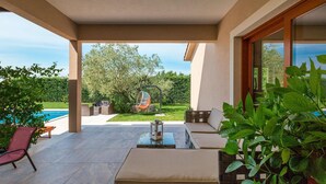 A covered outdoor seating area with a pool, a glass table, and a hammock. - Amazing home in Salambati (Salambati)