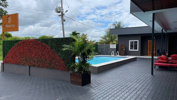 A modern building with a swimming pool, a covered outdoor seating area, and a sign indicating it is a hotel. - Queen's Two Bedroom Apartment (Paramaribo)