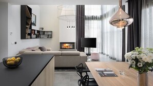 Una cocina moderna con una isla central, un comedor con mesa de madera y una sala de estar con sofá y chimenea.