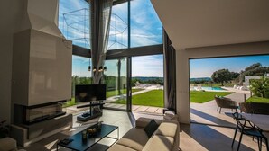 Una sala moderna con un televisor grande, asientos cómodos y vistas a una piscina y jardín.