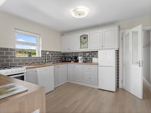 A modern kitchen with white cabinetry, a built-in oven, a microwave, and a refrigerator.