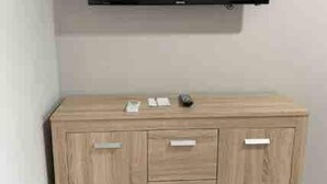 Un meuble en bois avec des tiroirs, et un téléviseur à écran plat fixé au-dessus.