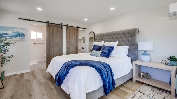 Un dormitorio con una cama grande, una mesita de noche con lámpara y una puerta corredera.