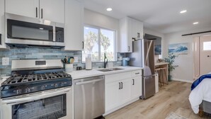 Una cocina moderna con armarios blancos, electrodomésticos de acero inoxidable y un amplio ventanal que proporciona luz natural.