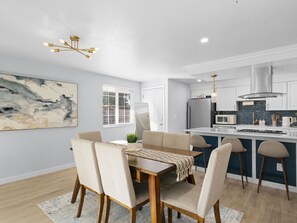 A modern kitchen with white cabinets, a stainless steel range hood, and a central island with bar stools.