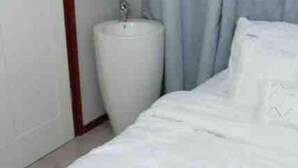 A hotel room with a bed, a white sink, and a mirror above it. - One Bedroom Apartment (Paramaribo)