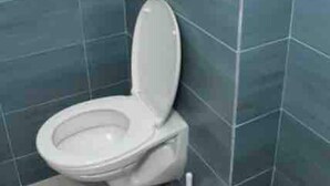 A bathroom with a toilet, a towel, and a toilet paper holder. - One Bedroom Apartment (Paramaribo)