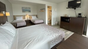 Quarto de hotel com duas camas, televisão, máquina de café e um quadro na parede.