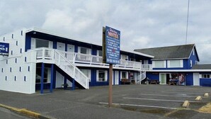 Um motel com estrutura em dois andares, área externa coberta e estacionamento.