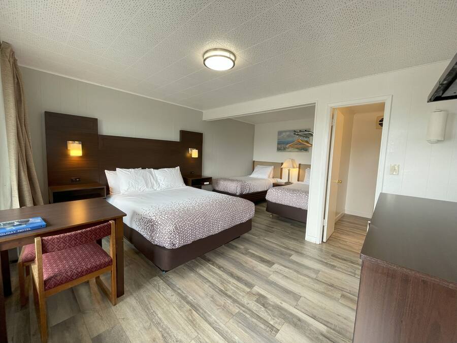 A hotel room with two beds, a desk, and a chair.