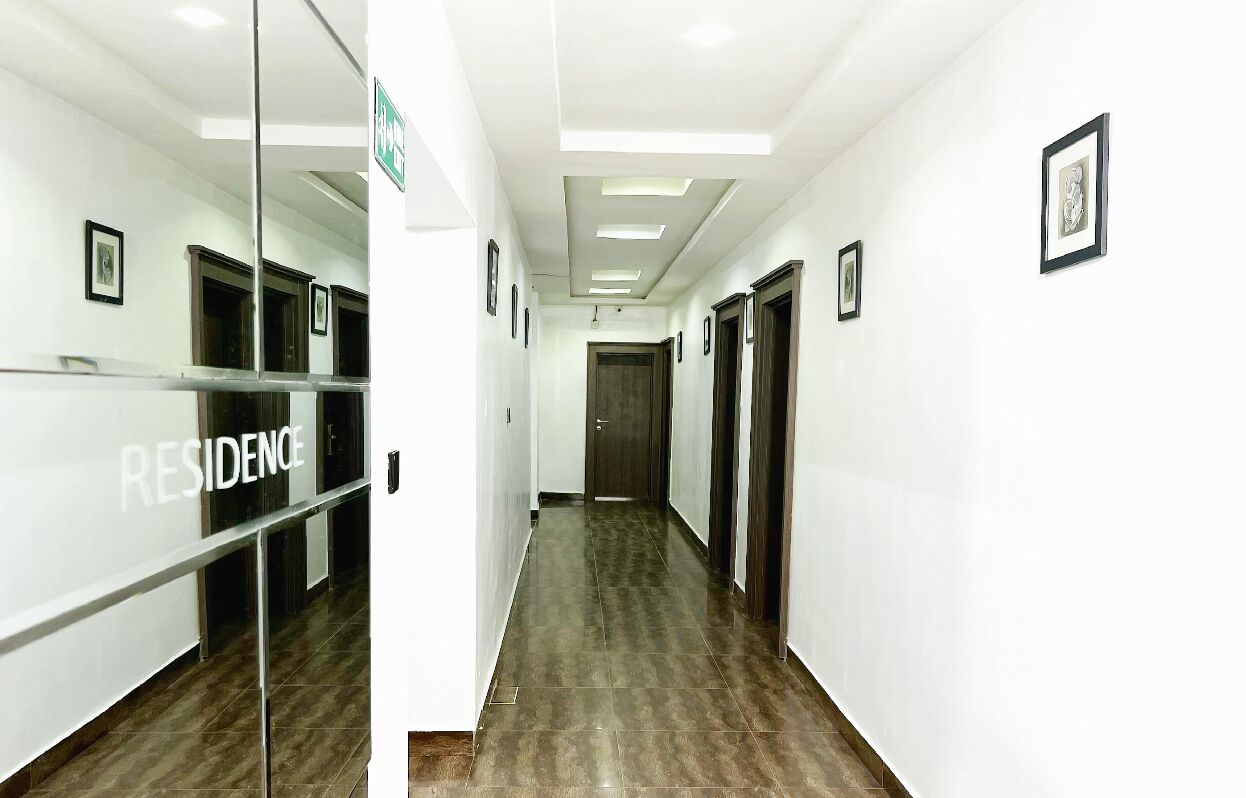 A long, narrow hallway with a glass partition on one side and a door at the end.