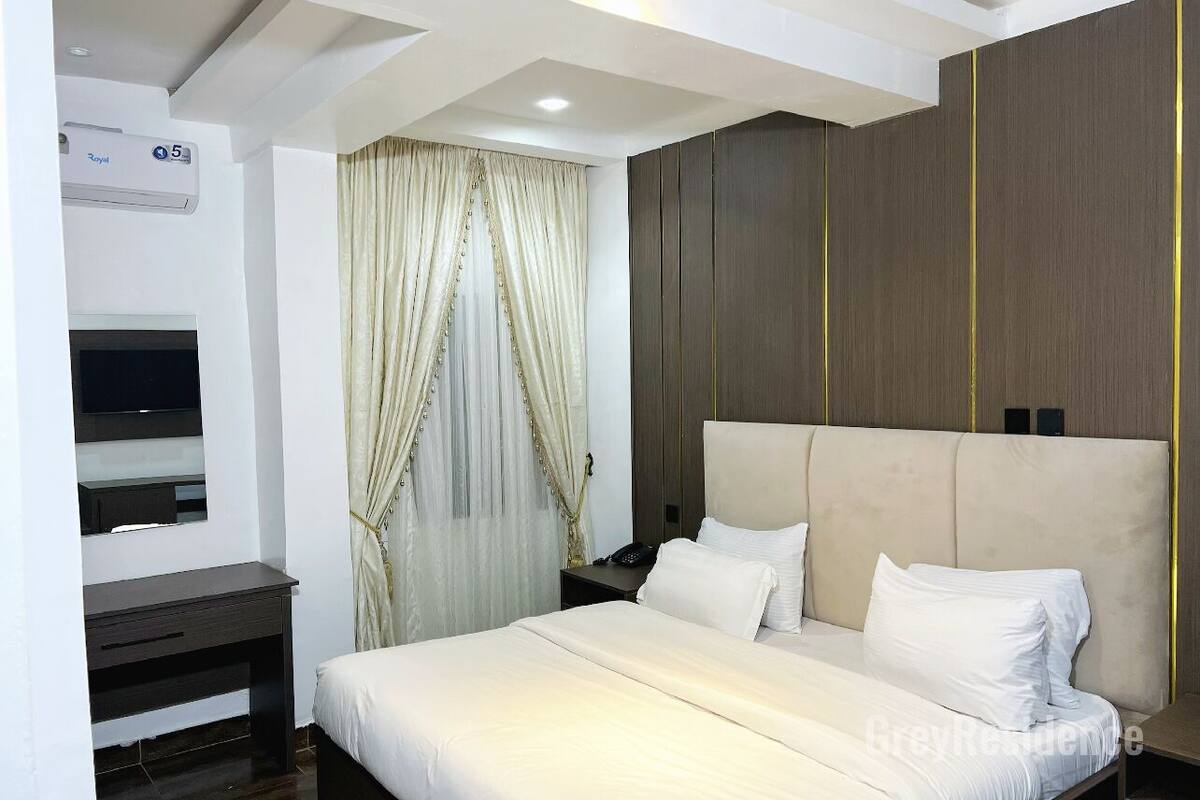 A hotel room with a bed, a desk, a TV, and a wardrobe.