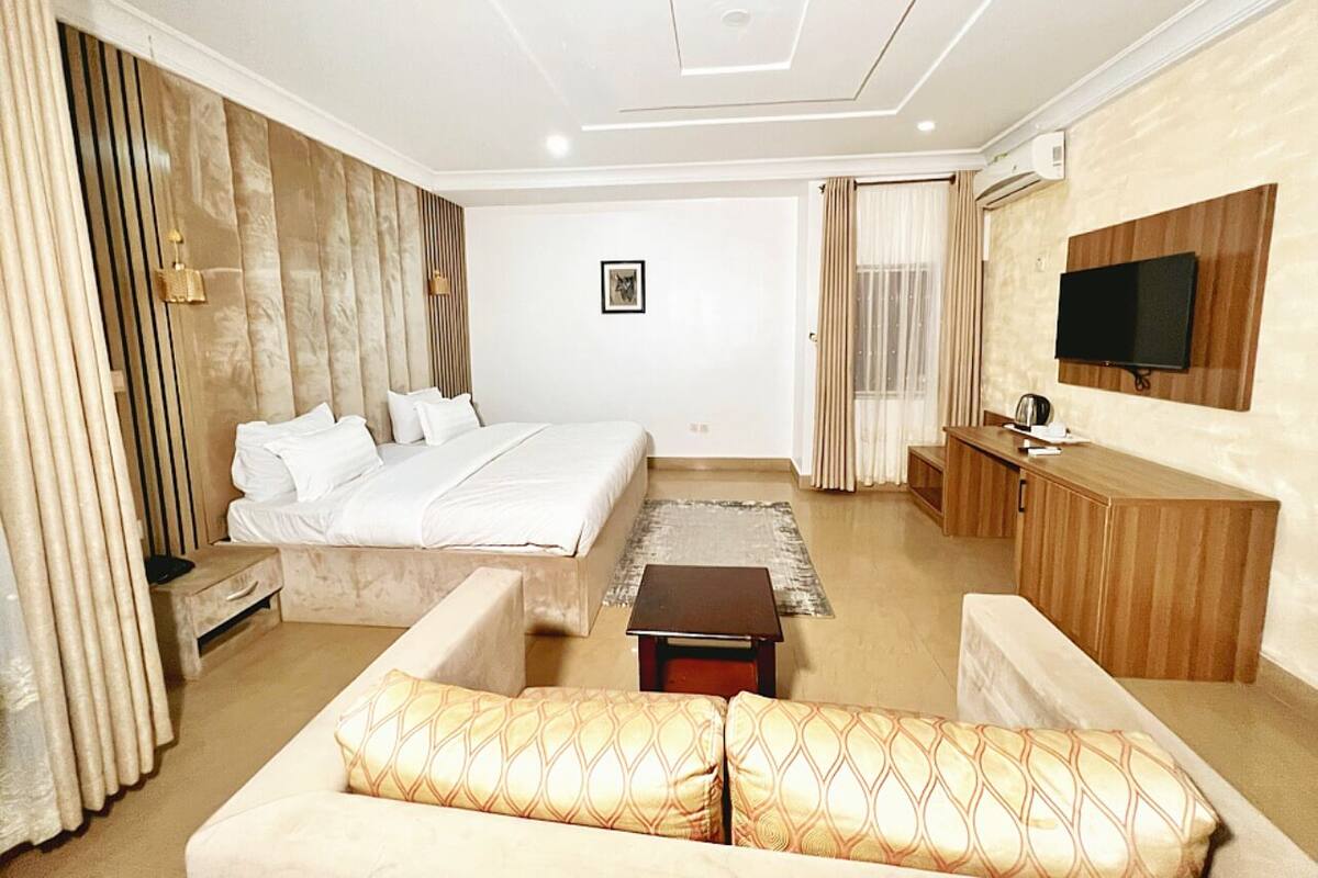 A hotel room with a bed, a sofa, a TV, and a desk.