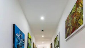A corridor with tiled floors and walls adorned with framed artworks. - Casa Hotel Nurandy  (Cartagena)