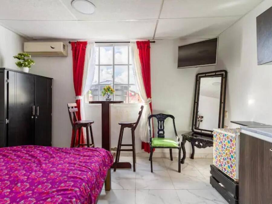 Quarto com cama, duas cadeiras, uma mesinha, espelho e armário.