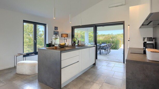 A modern kitchen with a large island, a dining area with a view, and a separate dining room. - Gorgeous home in Burici (Burici)