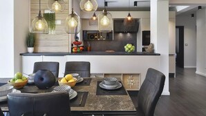 A modern kitchen with pendant lights, a dining area with a marble table, and a view of the adjacent living space. - Beautiful home in Pula (Pula)