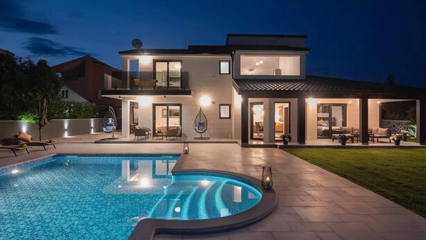 A modern two-story house with a swimming pool, outdoor seating, and a well-lit patio area. - Beautiful home in Pula (Pula)