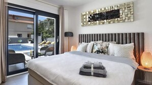 A modern bedroom with a large bed, a view of a pool, and a decorative wall piece. - Beautiful home in Pula (Pula)