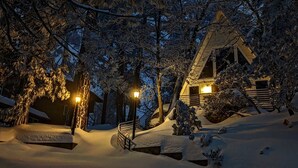 A snow-covered landscape with a wooden cabin and a staircase leading to a lit entrance. - Luxury summer Scandia A-Frame mountain Chalet +Hot Tub, EV & Pet friendly (Running Springs)