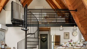 A spacious loft with a wooden staircase, a kitchen with bar seating, and a view of the living area. - Luxury summer Scandia A-Frame mountain Chalet +Hot Tub, EV & Pet friendly (Running Springs)