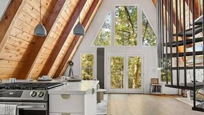 A modern kitchen with a stove, cabinets, and pendant lights. - Luxury summer Scandia A-Frame mountain Chalet +Hot Tub, EV & Pet friendly (Running Springs)