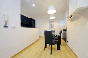 A modern kitchen with black cabinets, a dining table with chairs, and a directional sign on the wall. - Vaticano, nice apartment for 4 near Saint Peter (Roma)