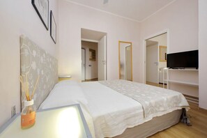 A bedroom with a bed, bedside table, lamp, and a television on a stand. - Vaticano, nice apartment for 4 near Saint Peter (Roma)
