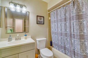 Bathroom features a sink, mirror, toilet, and shower with a patterned curtain.