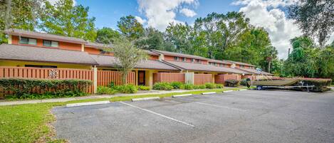 A row of motel buildings with a parking lot in front.