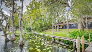 A wooden bridge over a pond with lily pads, surrounded by trees with Spanish moss. - Waterfront Dunnellon Retreat w/ River Access! (Dunnellon)