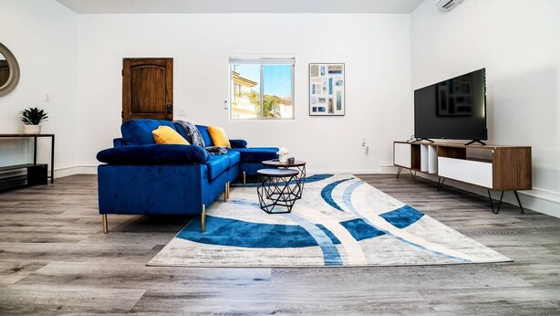 Un salon moderne avec un canapé bleu, un téléviseur et une grande fenêtre.