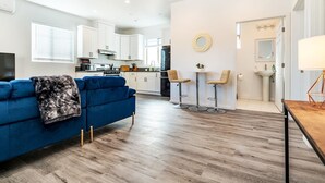 Un salon moderne avec un canapé bleu, une table basse et une cuisine en arrière-plan.
