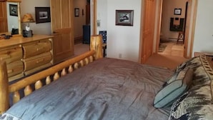 Un dormitorio con estructura de cama de madera, un aparador y un escritorio con lámpara.