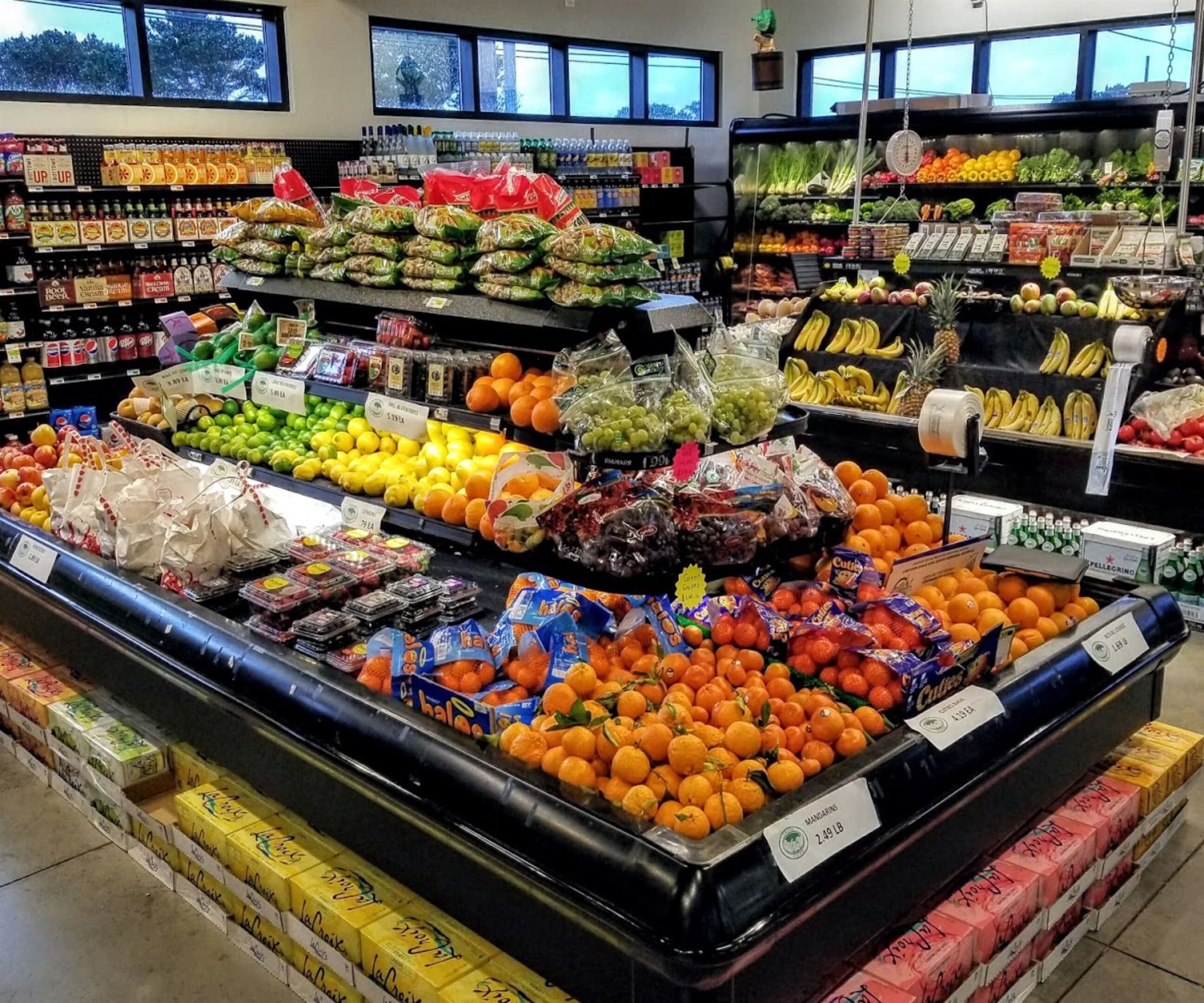 A grocery store with various fruits and vegetables on display, including oranges and bananas.