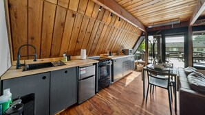 A modern kitchen with wooden walls, a built-in oven, and a dining area with a view of the outside.