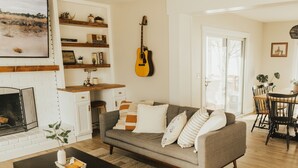 A cozy living room with a fireplace, a sofa, a coffee table, and a guitar hanging on the wall. - Rims view pet friendly home  (Billings)