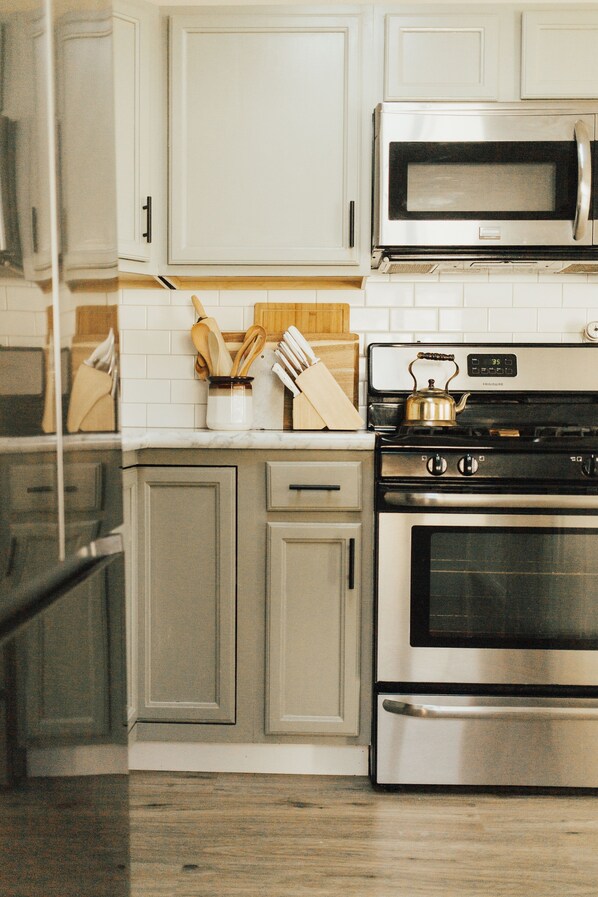 A kitchen with white cabinets, a stainless steel stove, and a microwave. - Rims view pet friendly home (Billings)