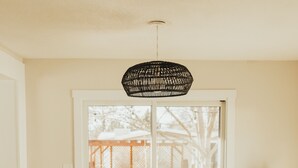 A dining area with a wooden table and chairs, a hanging light fixture, and a view through a glass door to an outdoor patio. - Rims view pet friendly home  (Billings)
