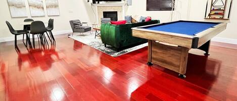 Un vaste salon doté d’une table de billard, d’une cheminée et d’un porte-queue.