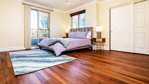 A bedroom with a bed, a nightstand, a lamp, and a large window.
