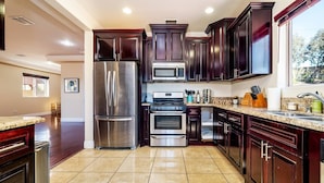 A modern kitchen with dark wood cabinets, stainless steel appliances, and a granite countertop.