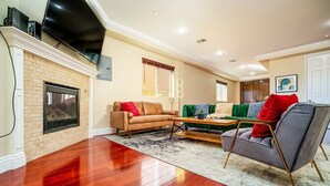 A living room with a fireplace, a sofa, a green couch, a coffee table, and a TV mounted on the wall.